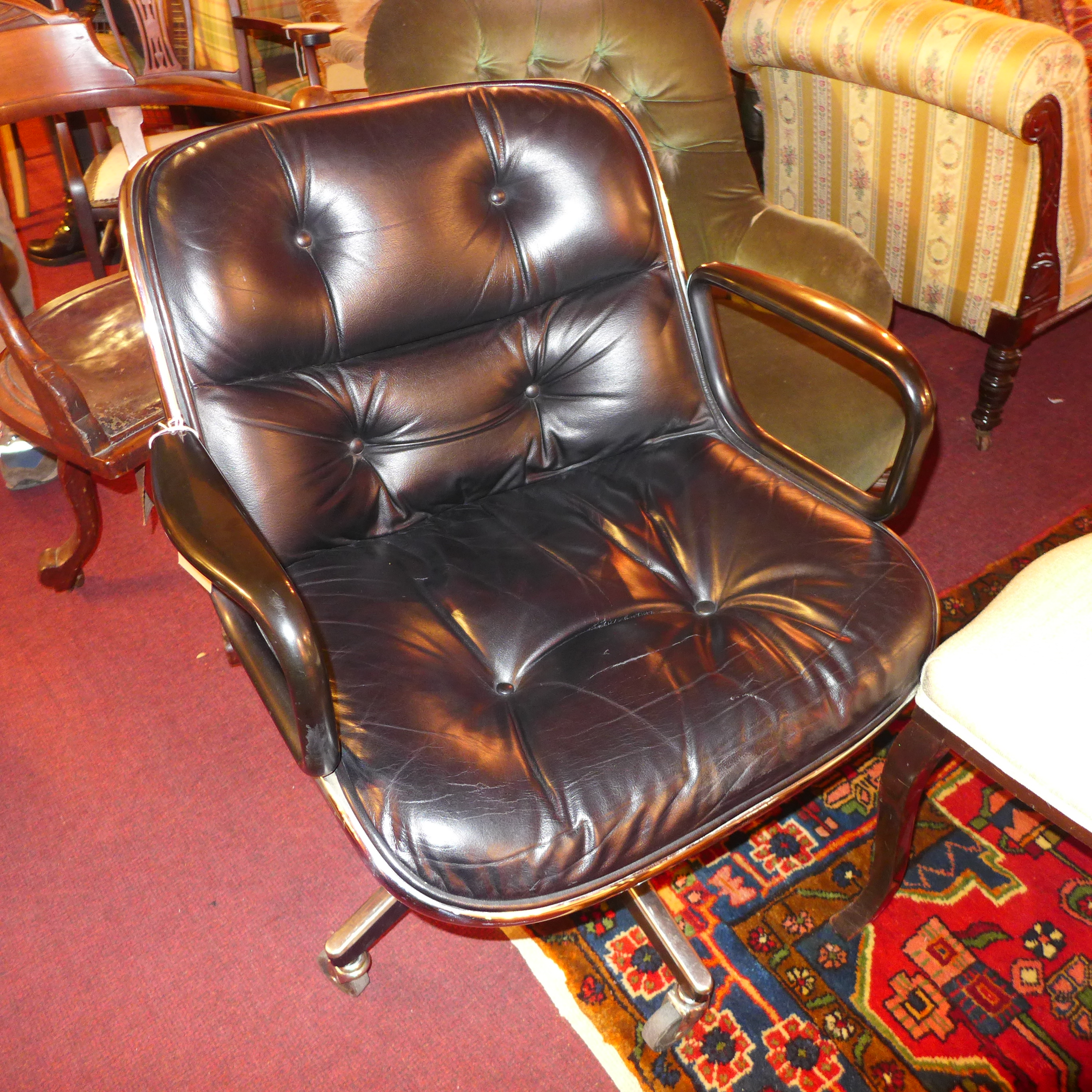 A knoll Pollack executives chair upholstered in buttoned black leather and raised on swivel