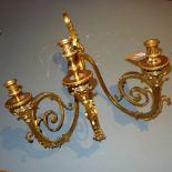 A pair of Rococo style gilt metal triple branch wall sconces with ornate leafy detail