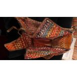 A north west Persian saddle bag, having bands of brightly coloured repeating motifs, leather straps,