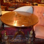 A Georgian oak occasional table the circular top raised on turned column and triform supports