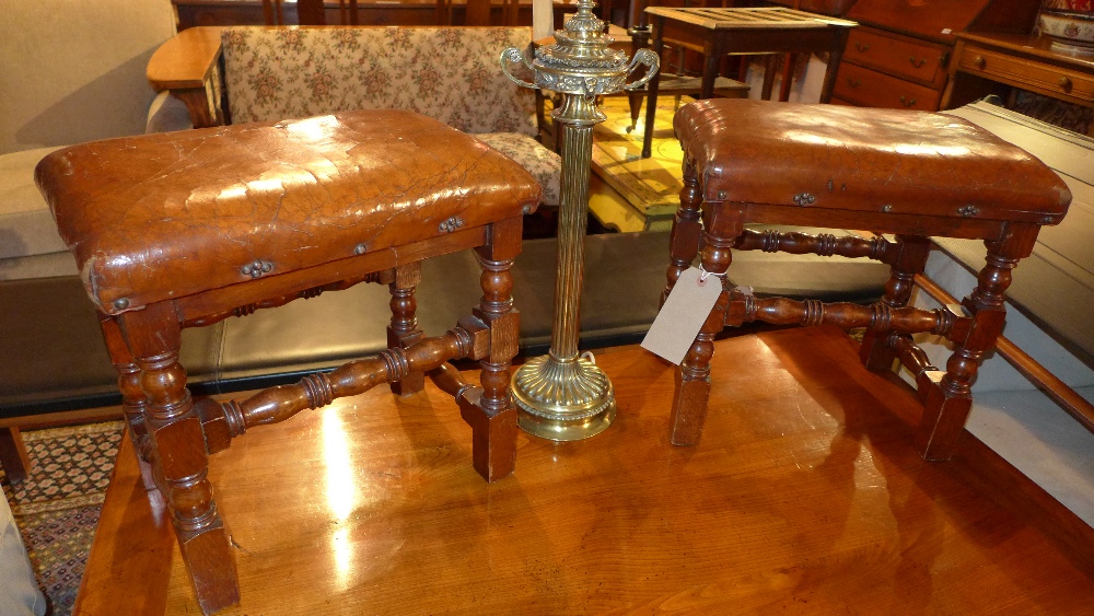 A pair of early 20th century tan leather and oak stools on stretchered supports