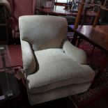 A Howard style armchair upholstered in beige fabric and raised on turned supports and castors