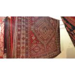 An antique rug, having two medallions on a red field with flowerhead designs,