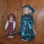 A pair of porcelain dolls on stands, one