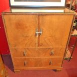 A 1970's cabinet with panel doors over two drawers on block feet