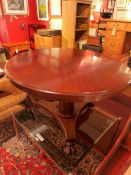 A mahogany circular tilt top table on tripod base with claw caster feet