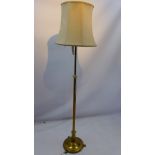 A brass standard lamp in the classical taste raised on circular base and three scroll feet H 145cm