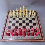 A Chinese Ivory chess set, the figures mounted on puzzle balls, half stained red,