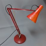 A retro angle poise lamp raised on circular base,