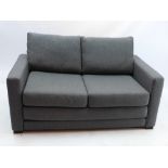 A contemporary John Lewis two seater sofa bed, upholstered in grey, raised on block supports,