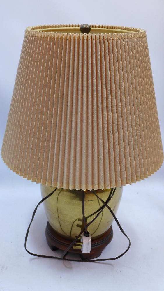 A Chinese style brass table lamp of ovoid form and raised on carved hardwood base,