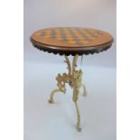 A circular games table raised on white painted cast iron base in the classical style,