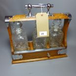 An early 20th century oak tantalus with three cut glass decanters and silver plated mounts (with