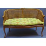 A caned two seater settee with upholstered cushion on cabriole supports,