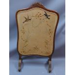 A 19th century walnut fire screen with embroidered silk and raised on scroll legs,