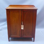 An Edwardian mahogany cupboard with satinwood inlay and raised on square tapered legs,