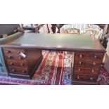 An early 20th century mahogany pedestal desk with an arrangement of eight graduating drawers raised