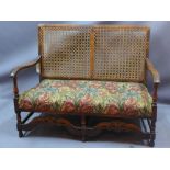 An early 20th century mahogany two seater canape with cane back rest and upholstered seat,