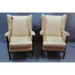 A pair of 1950's wing back armchairs upholstered in yellow fabric