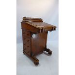 A Victorian walnut davenport with four drawers and four faux drawers raised on bun feet and castors