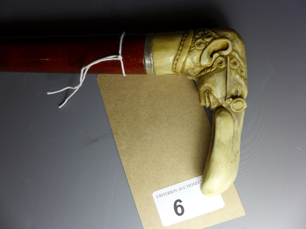 A walking stick with carved horn handle in the form of a Jewish scholar. With silver collar.