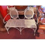 A white painted distressed metal garden bench having oval detail to the back H:94cm W:108cm D:45cm