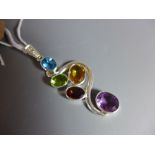 A silver pendant set with amethyst, blue topaz, ruby, peridot and amber quartz.