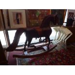 A hand carved pitch pine rocking horse, having tan leather reins and saddle.