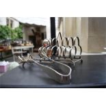 A silver plated pair of kitchen tongs together with silver plated toast rack
