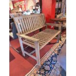 A weathered teak two seater garden bench