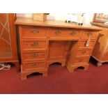 An early 20th Century pine knee hole desk with an arrangement of nine drawers and central cupboard