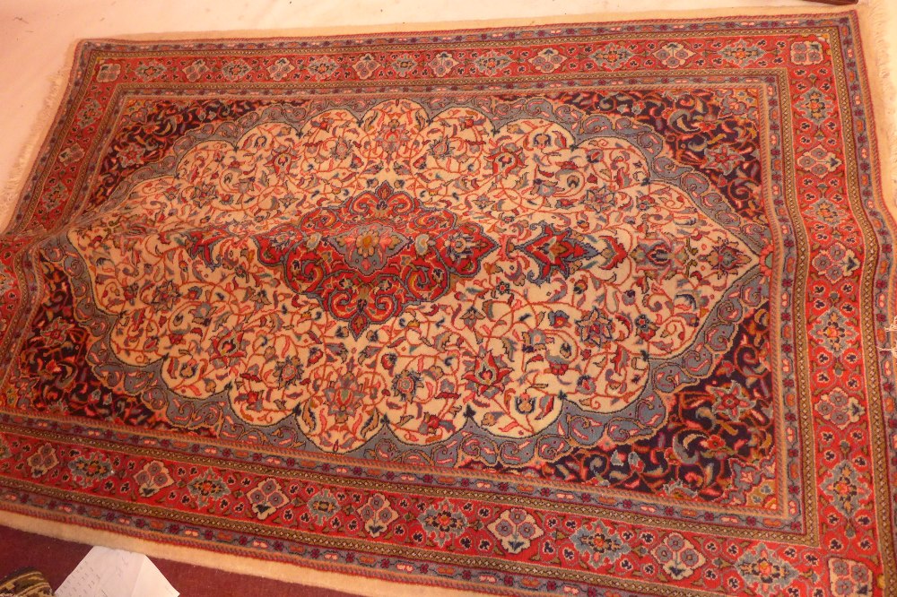 A Persian Kashan rug having a medallion on an ivory field with blue spandrels,