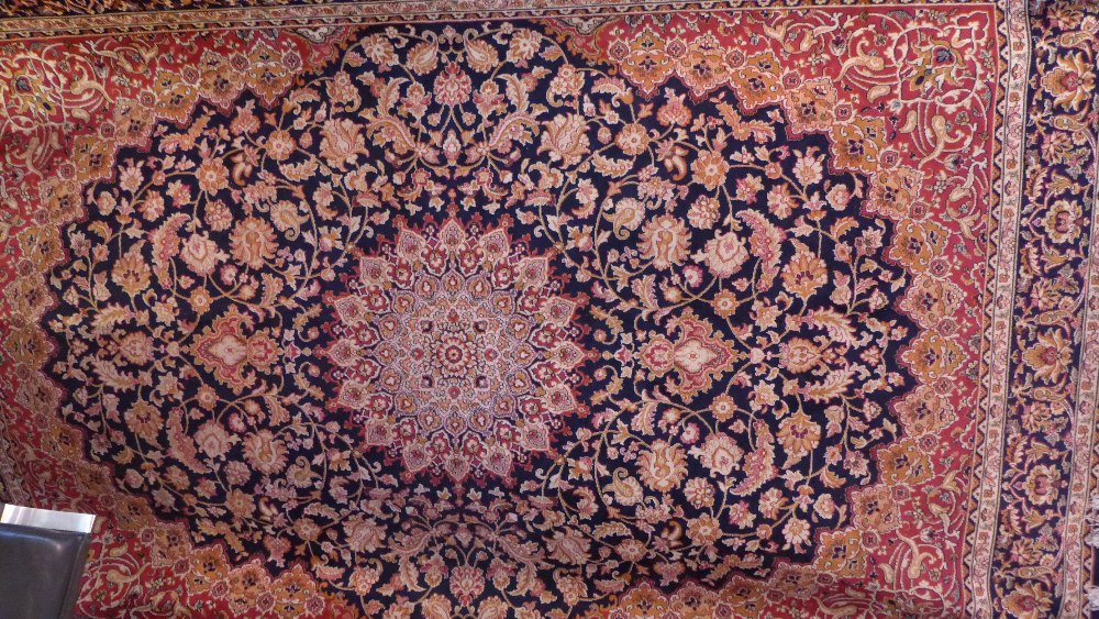 A Keshan style rug having a medallion on a midnight blue field with red spandrels,
