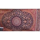 A Keshan style rug having a medallion on a midnight blue field with red spandrels,