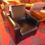 An Art Deco style black leather armchair of angular form, raised on block supports.