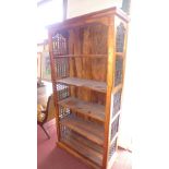 A teak open bookcase having wrought iron grille sides and five shelves H:180cm W:91cm D:37cm