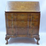 An early 20th Century Queen Anne style burr walnut bureau with hinged flap above three drawers and