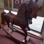 A hand carved pitch pine rocking horse, having tan leather reins and saddle.