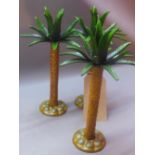 A set of three metal candlesticks in the form of palm trees