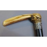 An ebonised walking cane with carved bone handle in the form of a Jewish cricket player with silver