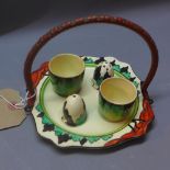 A Clarice Cliff hand painted cruet set and two egg cups on stand with Delecia bizarre pattern