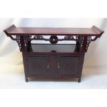 A Chinese hardwood alter cabinet with two items above two cupboard doors,