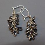 A pair of silver earrings set with sapphires in the form of grapes