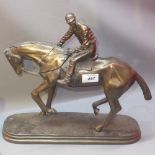 A bronzed resin statue of a jockey on a horse.