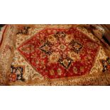 A Heriz style carpet with central floral diamond medallion on a red ground contained by borders.