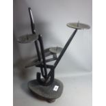 A modernist black steel candle stick holder on ball feet.