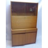 A vintage 20th Century teak bureau having two sliding glass doors above a pull down desk unit and