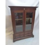 A 20th Century mahogany bookcase with two glazed doors above four drawers raised on carved bracket