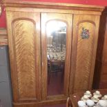 A Victorian walnut triple wardrobe with central mirrored door flanked by two doors enclosing linen