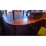 An oak drop leaf dining table raised on tapered legs,